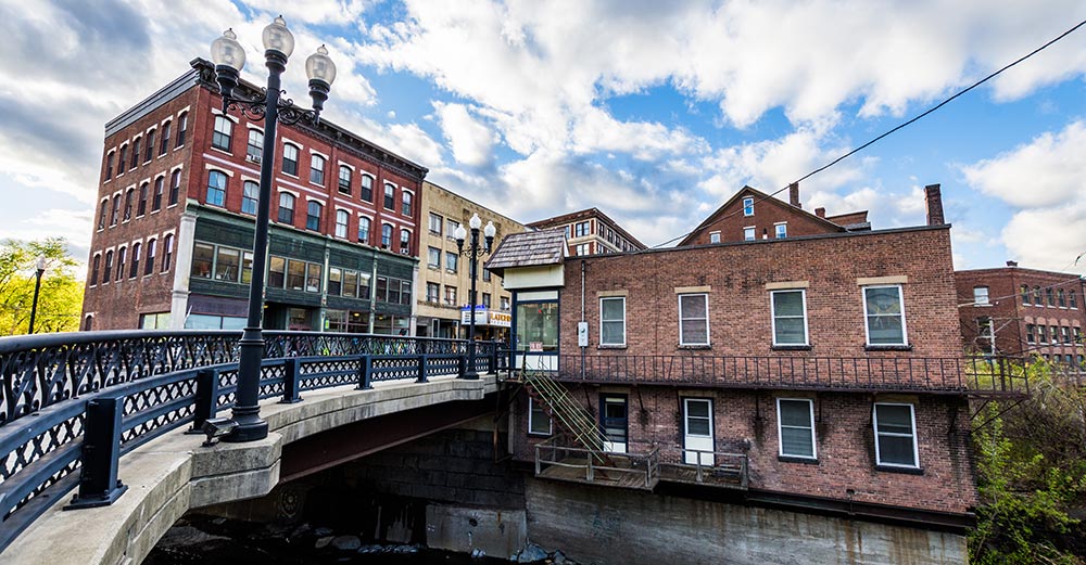 A small bridge over Whetstone Creek is flanked by historical commercial and residential buildings on the south end of Main Street in Brattleboro, Vermont.