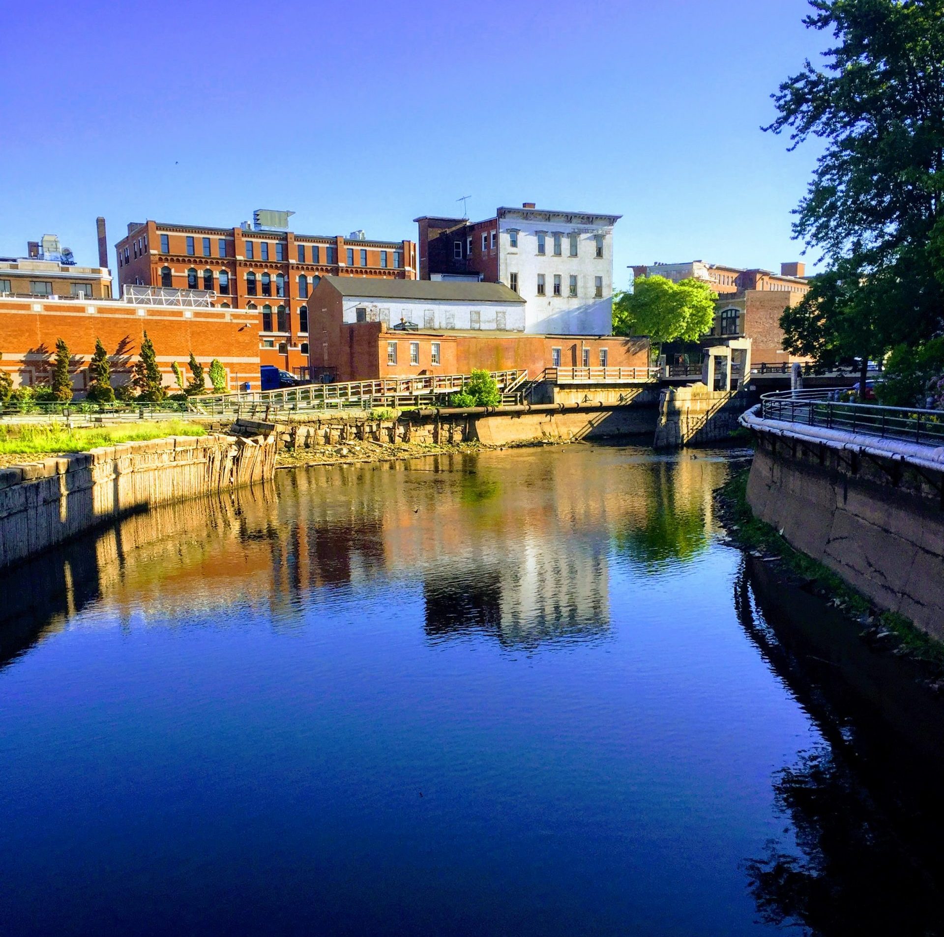 Historical industrial buildings that have been redeveloped into mixed-use residential and commercial buildings line a canal