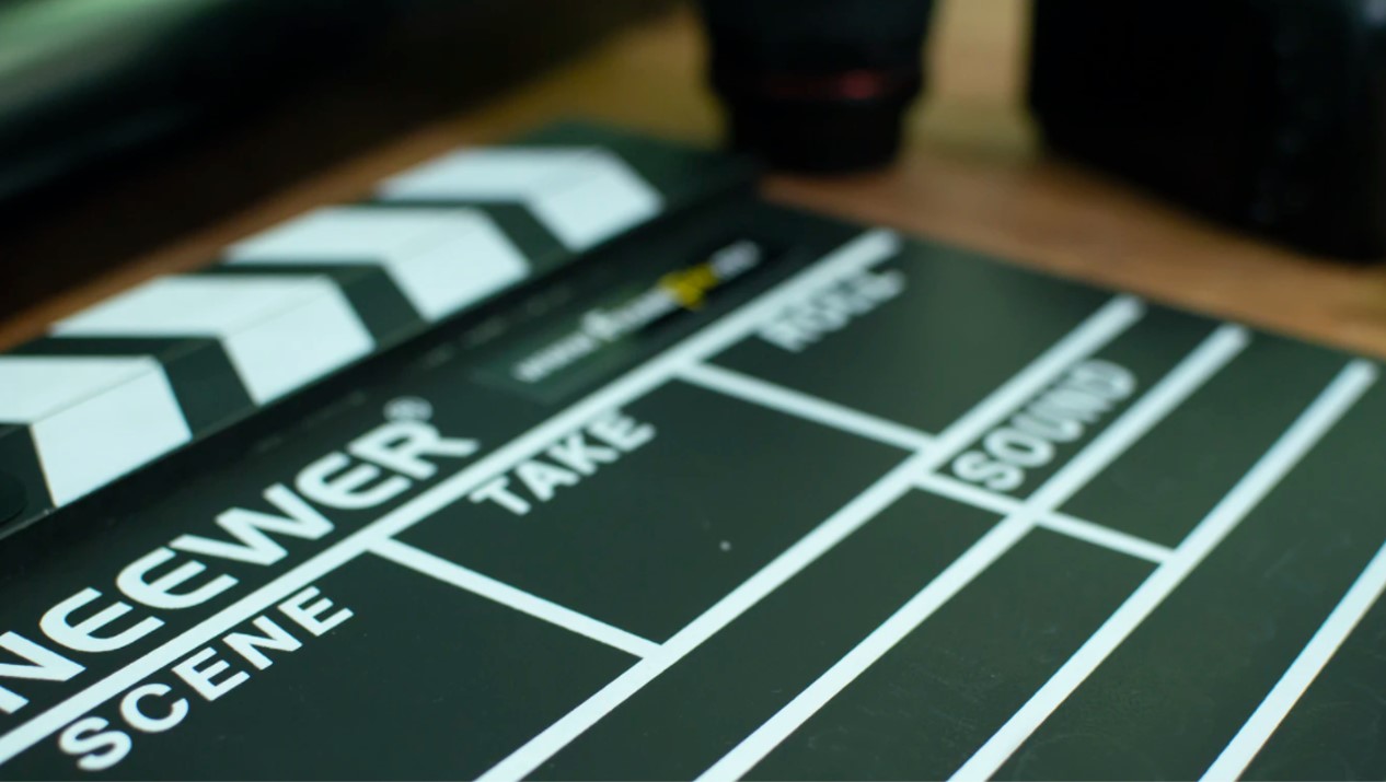 Close up image of a green and white film production clapperboard with spaces to fill in "scene," "take," "roll," and "sound" information