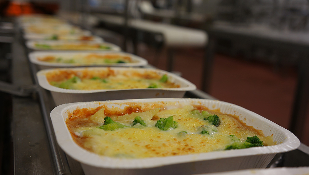 A photo of trays of heat-and-eat dinners on a food production factory conveyor belt