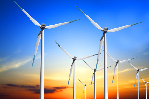 Multiple white wind energy turbines at sunset