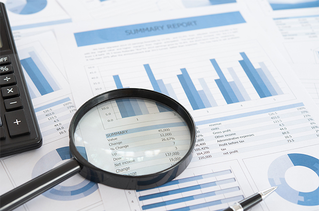 impact analysis for navigator | Camoin Associates Magnifying glass sits on print outs of data analysis tables