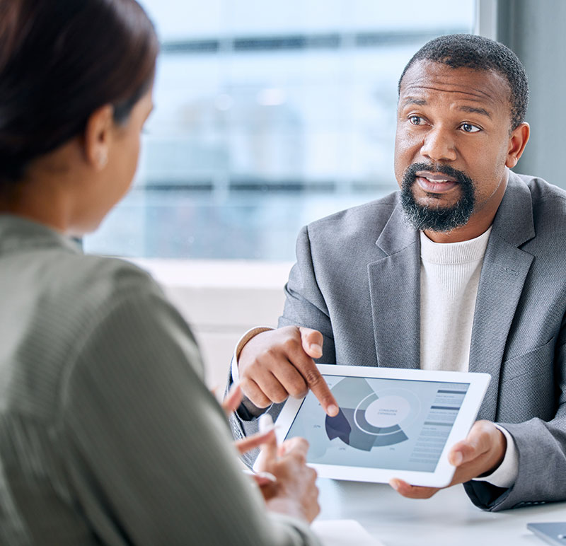 A man presents data to a woman in a one-on-one meeting