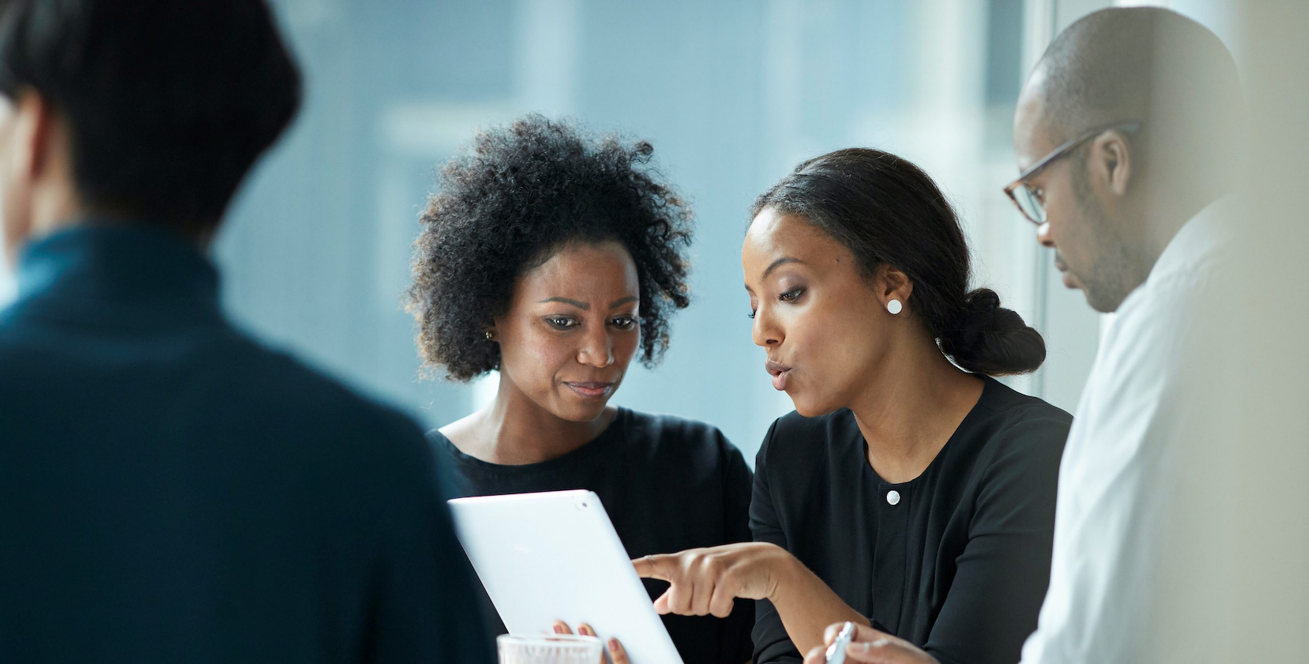Four BIPOC people review a business plan on a laptop in a meeting