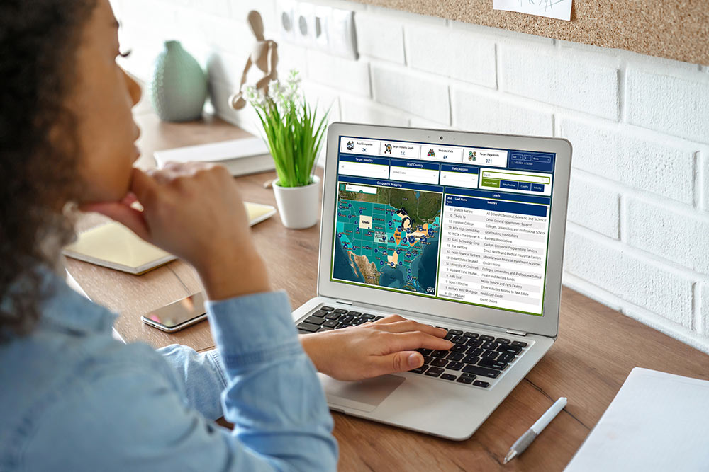 A woman sitting at a desk looks at a ProspectEngage map on her laptop computer