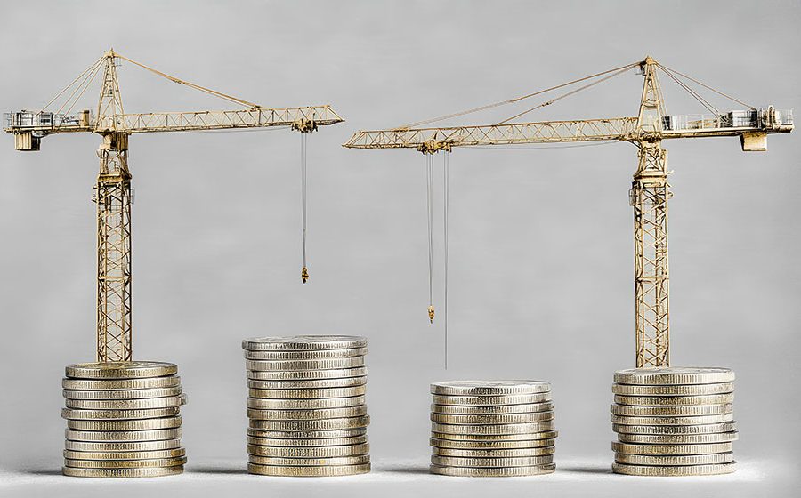Four stacks of coins with two construction cranes behind them illustration financing for development projects